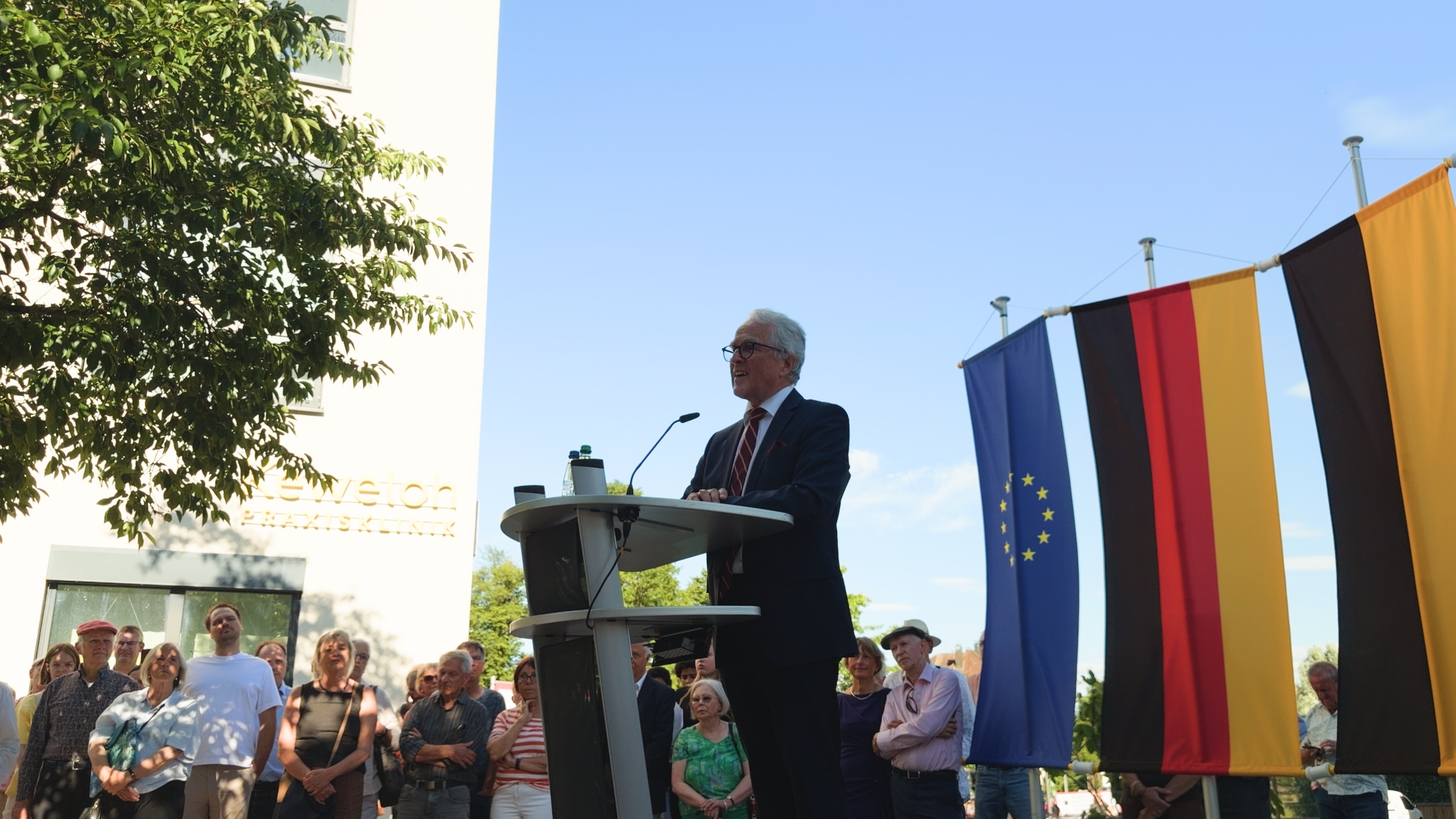 Rüdiger Freiherr von Fritsch spricht bei der Einweihung am Rednerpult, umgeben von Publikum und Europa- und Deutschlandflaggen.